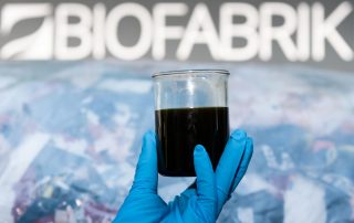 יד של פועל במפעל של ביופבריק שבבית הזיקוק וויט ריפיינרי בסקסוניה, גרמניה, מחזיק כוס של נפט ממוחזר
